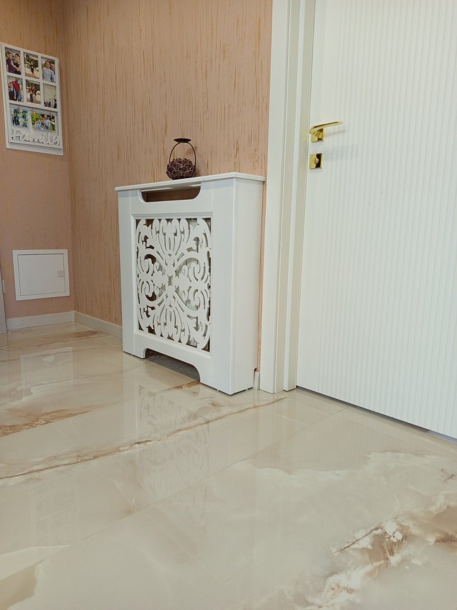 Mască ornamentală albă, lângă ușă, pe podea de marmură